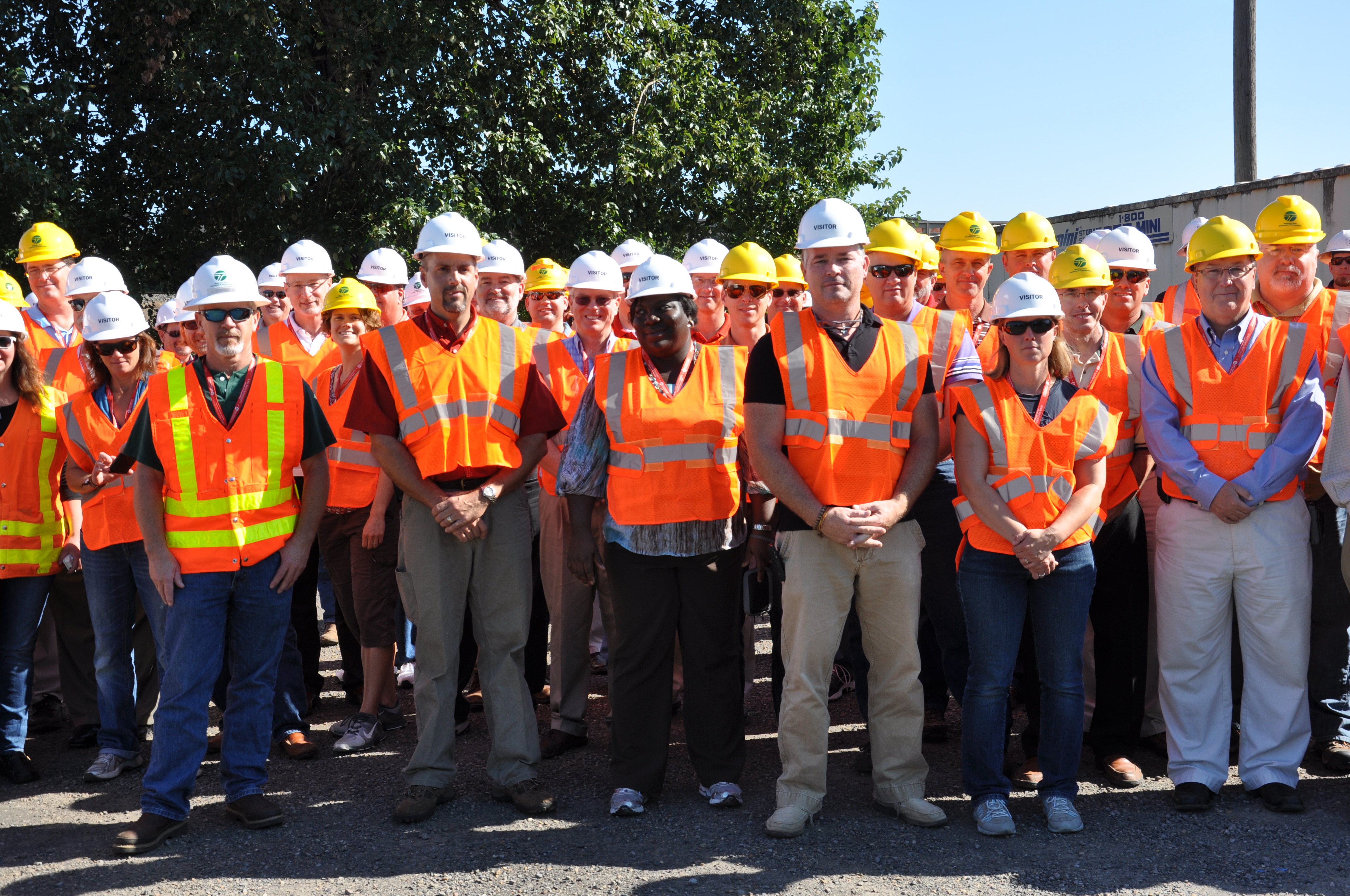 Group of people at a site tour wearing hard hats and reflective vests